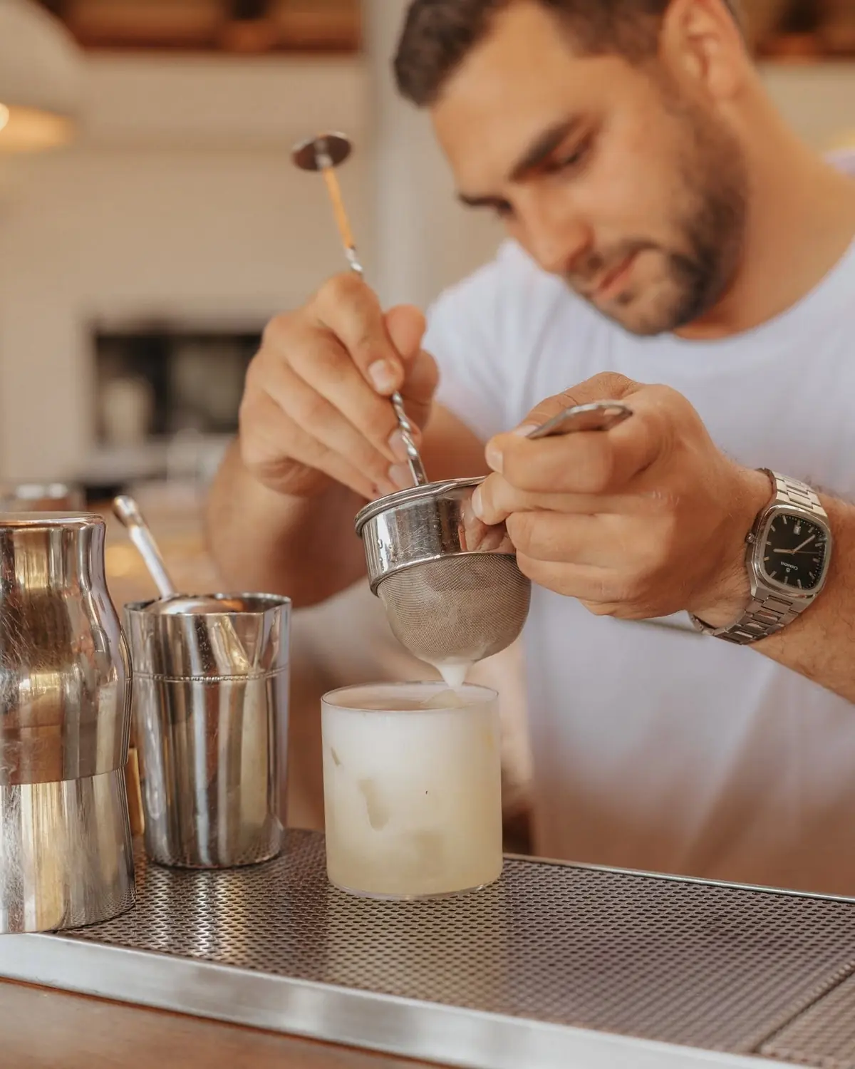 A bartender straining a cocktail at the bar