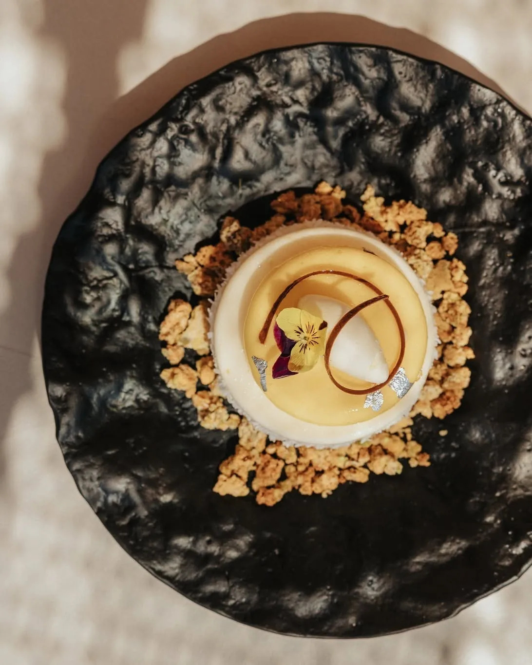 Dessert with an edible flower on black ceramic