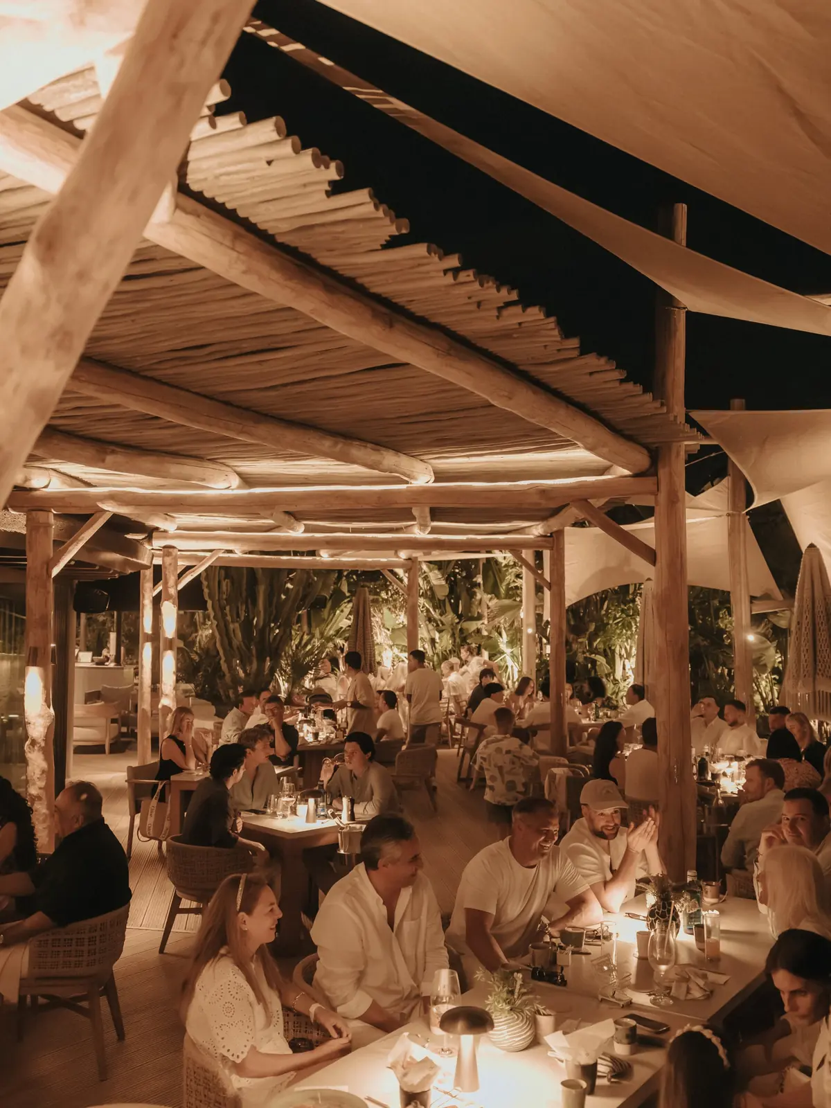 The dining room full in the evening beneath the reed roof