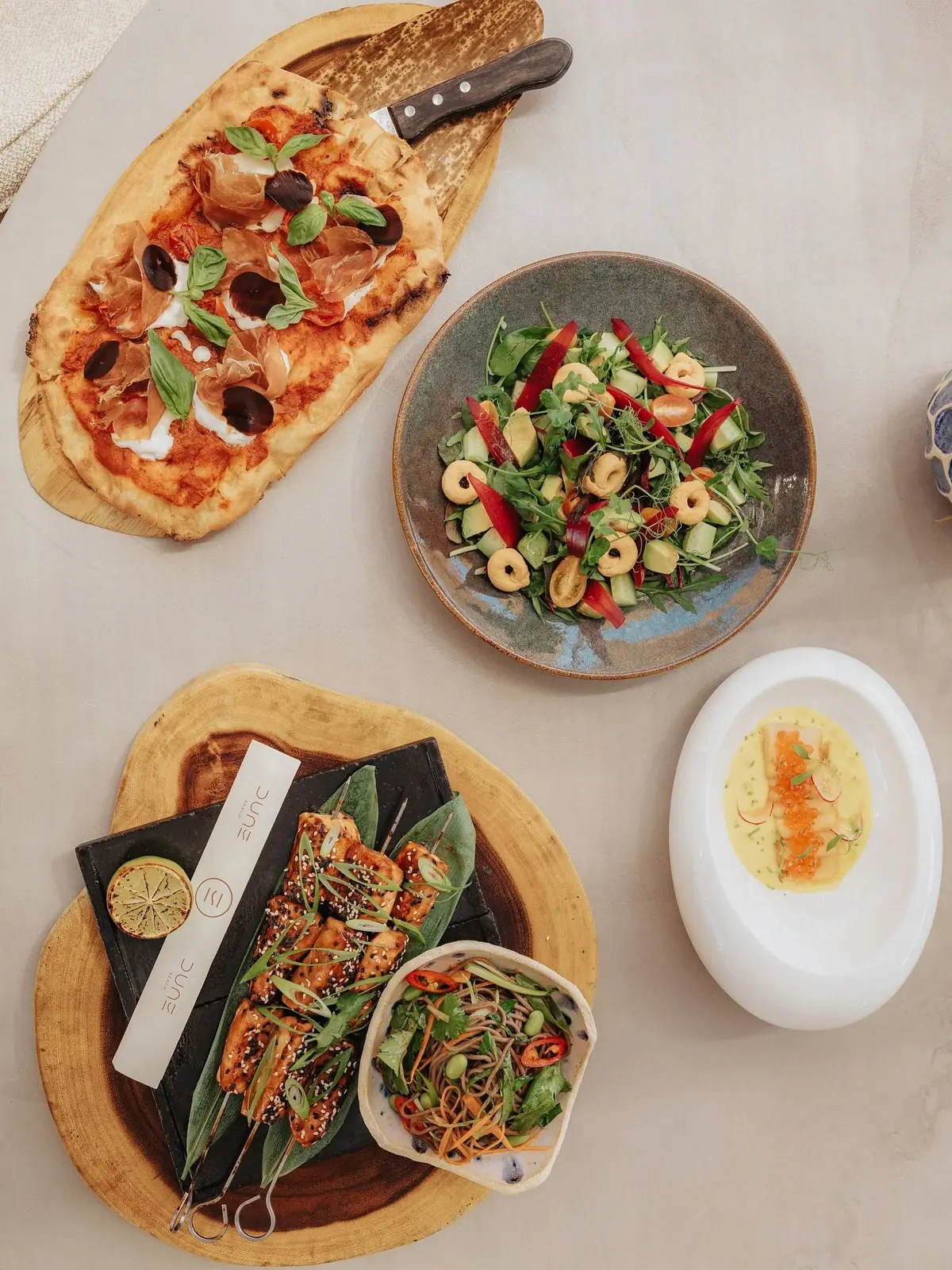 Pinsa, salad and skewers served across wooden boards